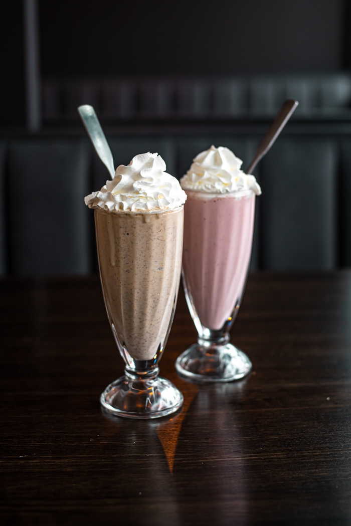 Close-up of a thick and creamy chocolate milkshake in a tall glass with whipped cream on top.